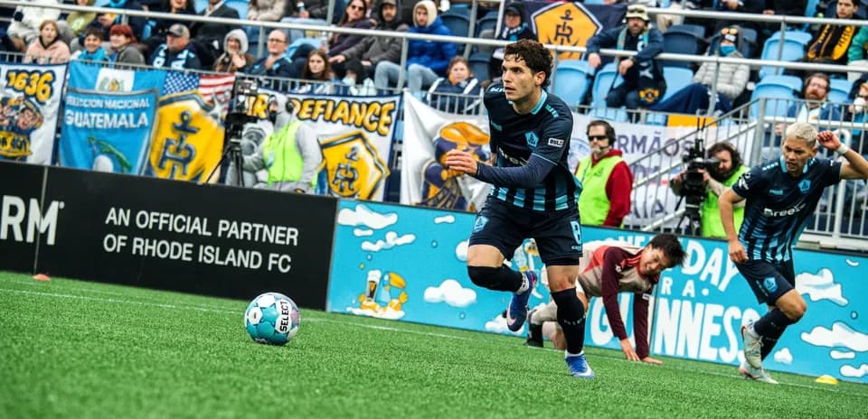Player advancing with ball during Rhode Island match