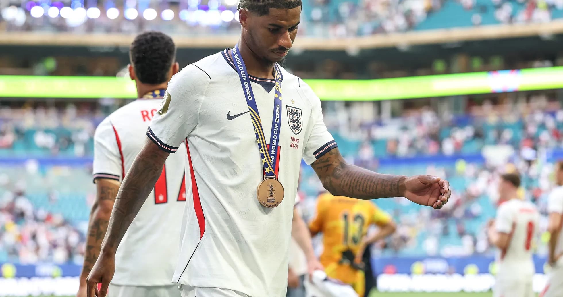 Player walking off field wearing bronze medal