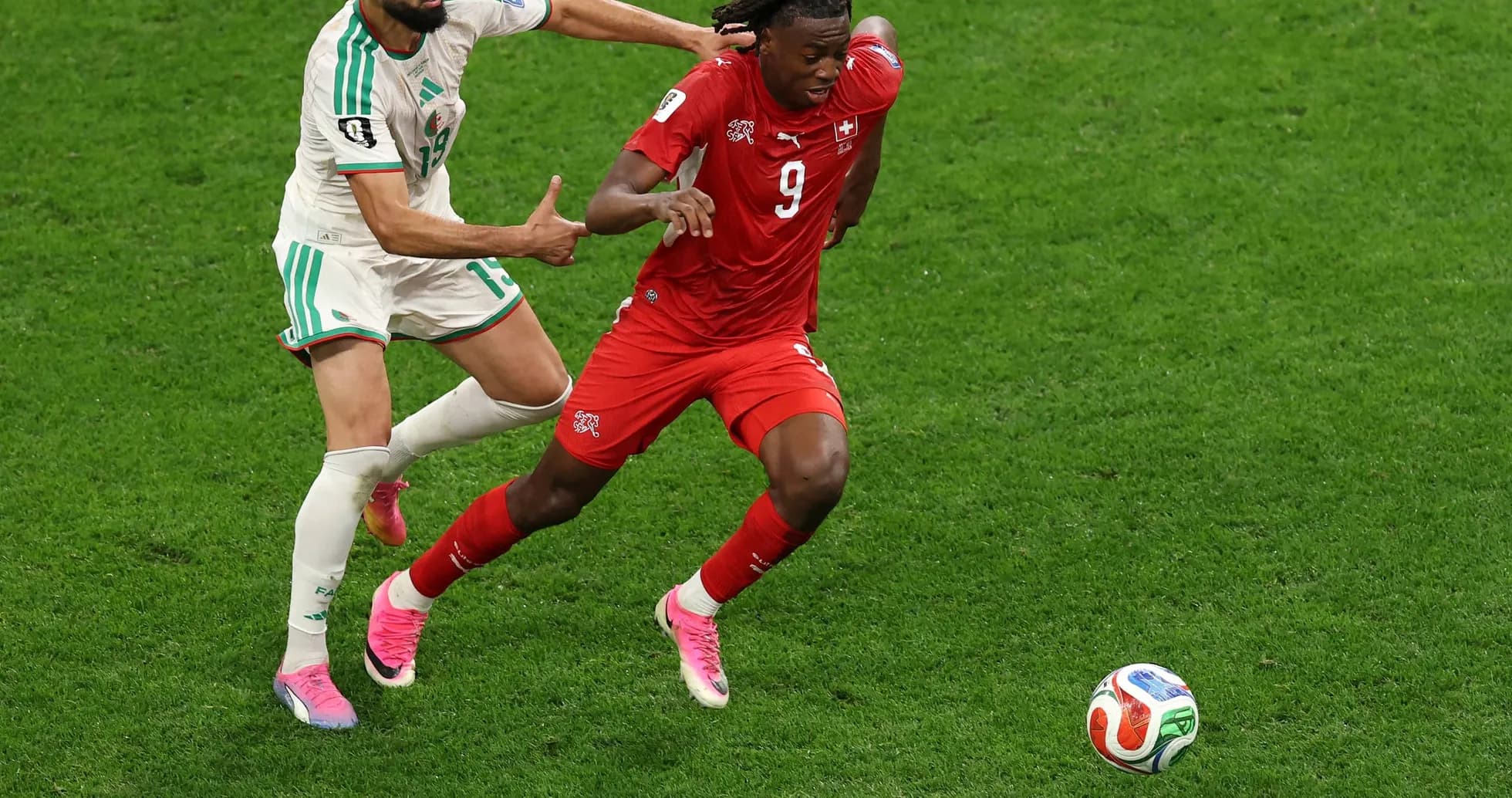 Player from Switzerland evading Algerian defender