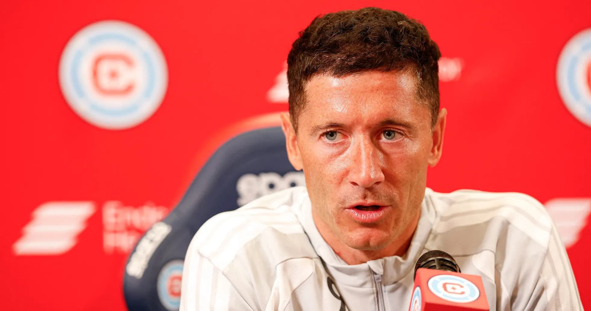 Player speaking at press conference with red backdrop