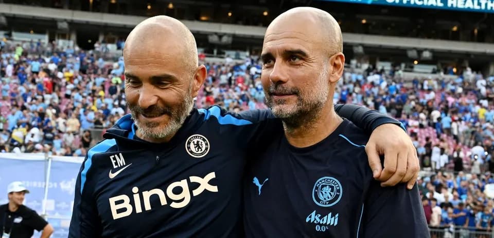 Two football managers smiling together on the pitch