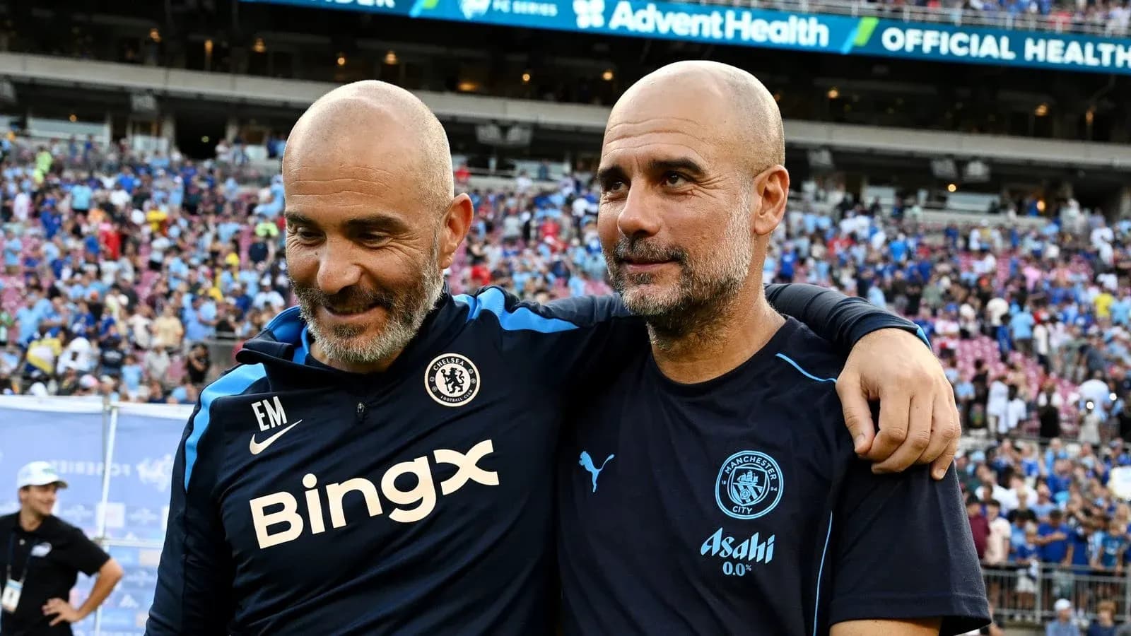 Two football managers smiling together on the pitch