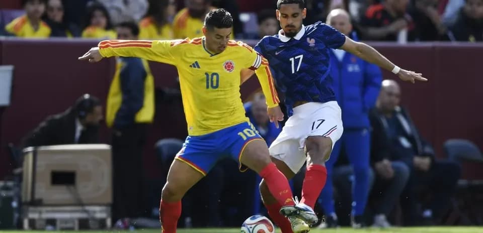 Colombian player challenges French player for the ball