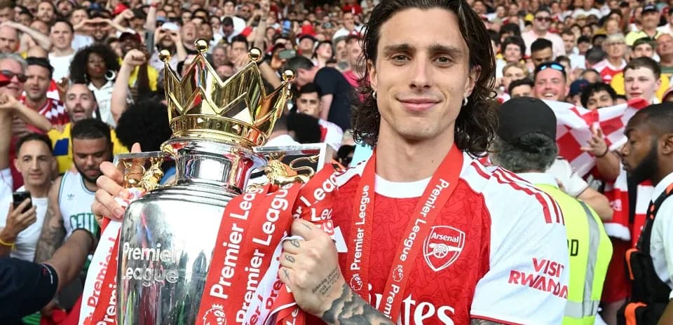 Player holding Premier League trophy with fans in background