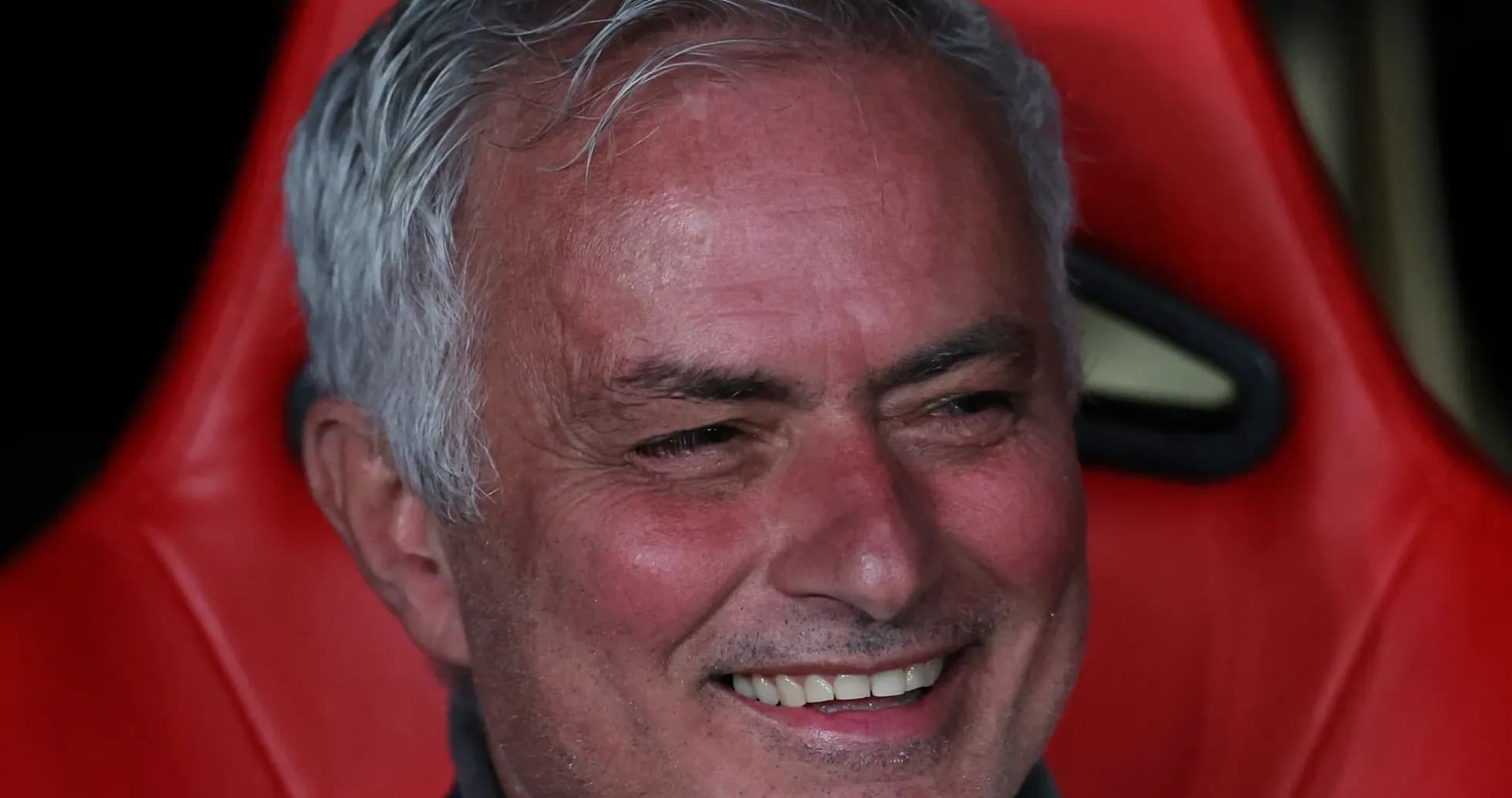 Coach sitting on bench during match with smile