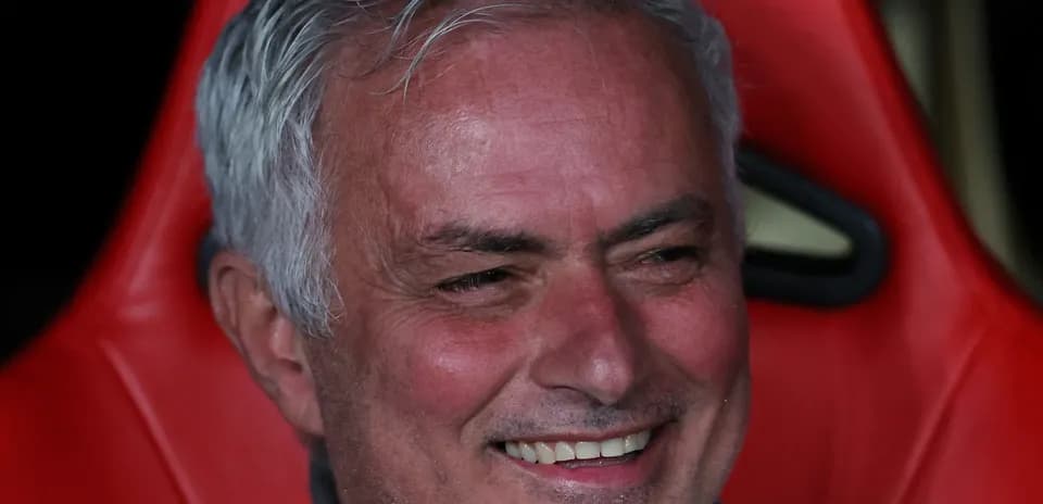 Coach sitting on bench during match with smile