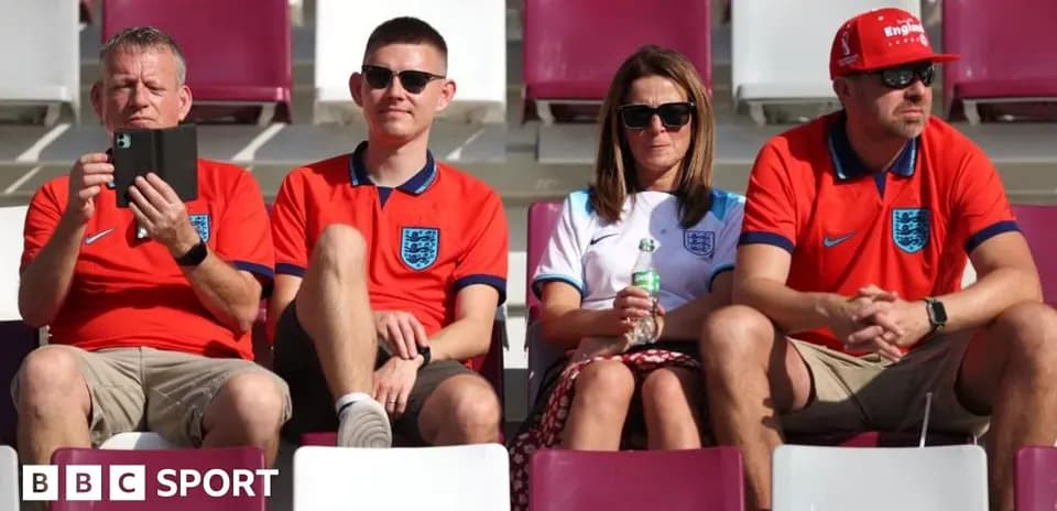 Fans wearing England jerseys sitting in stadium