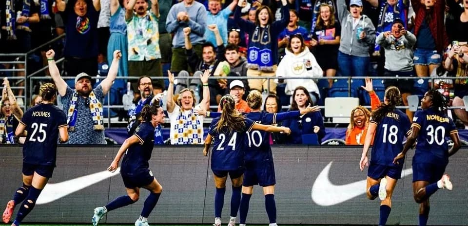Players celebrating goal with fans in stadium