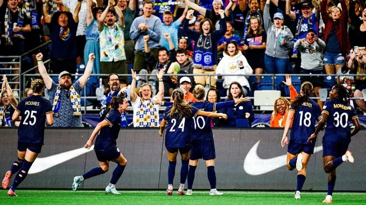 Players celebrating goal with fans in stadium