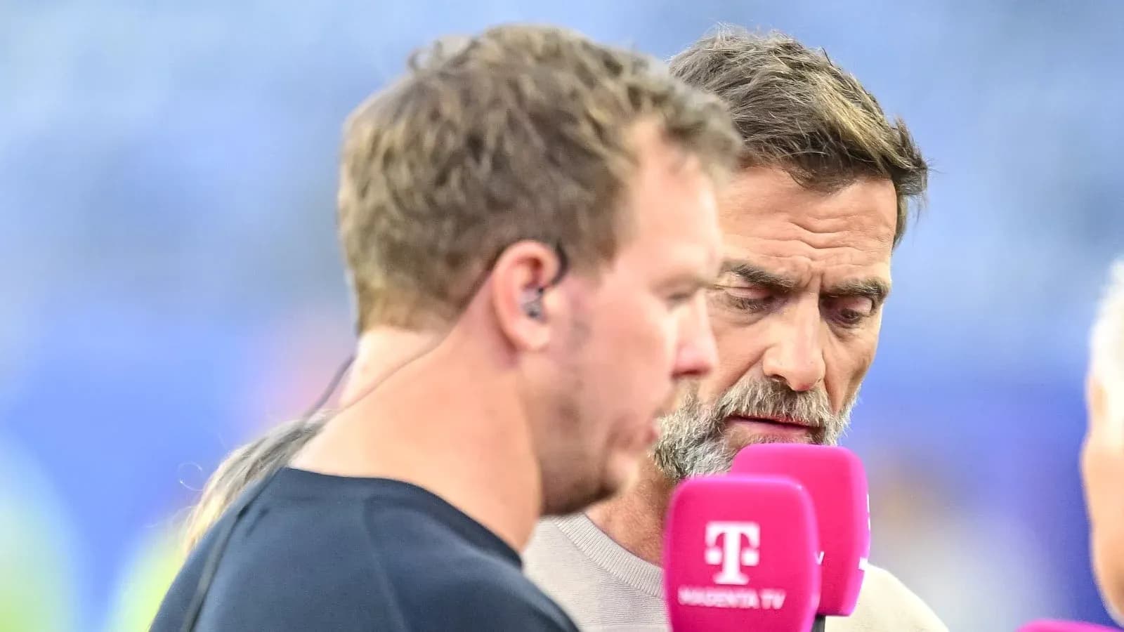 Two men speaking into microphones during an interview