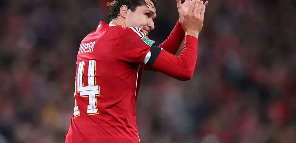 Player in red jersey applauding fans after match