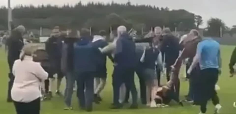 Crowd gathering around a fallen player on field