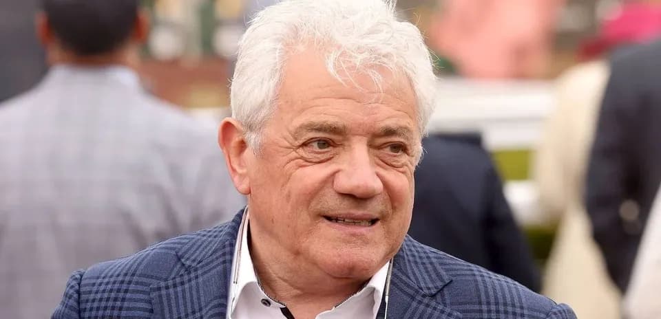 Man with white hair wearing a blue checked blazer