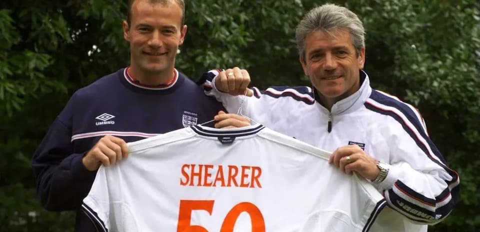 Two men holding an England football shirt with Shearer 50