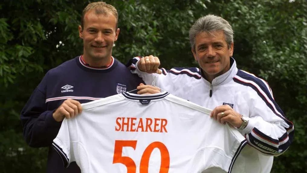 Two men holding an England football shirt with Shearer 50