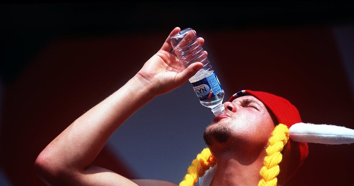 Person drinking water from a bottle wearing a hat