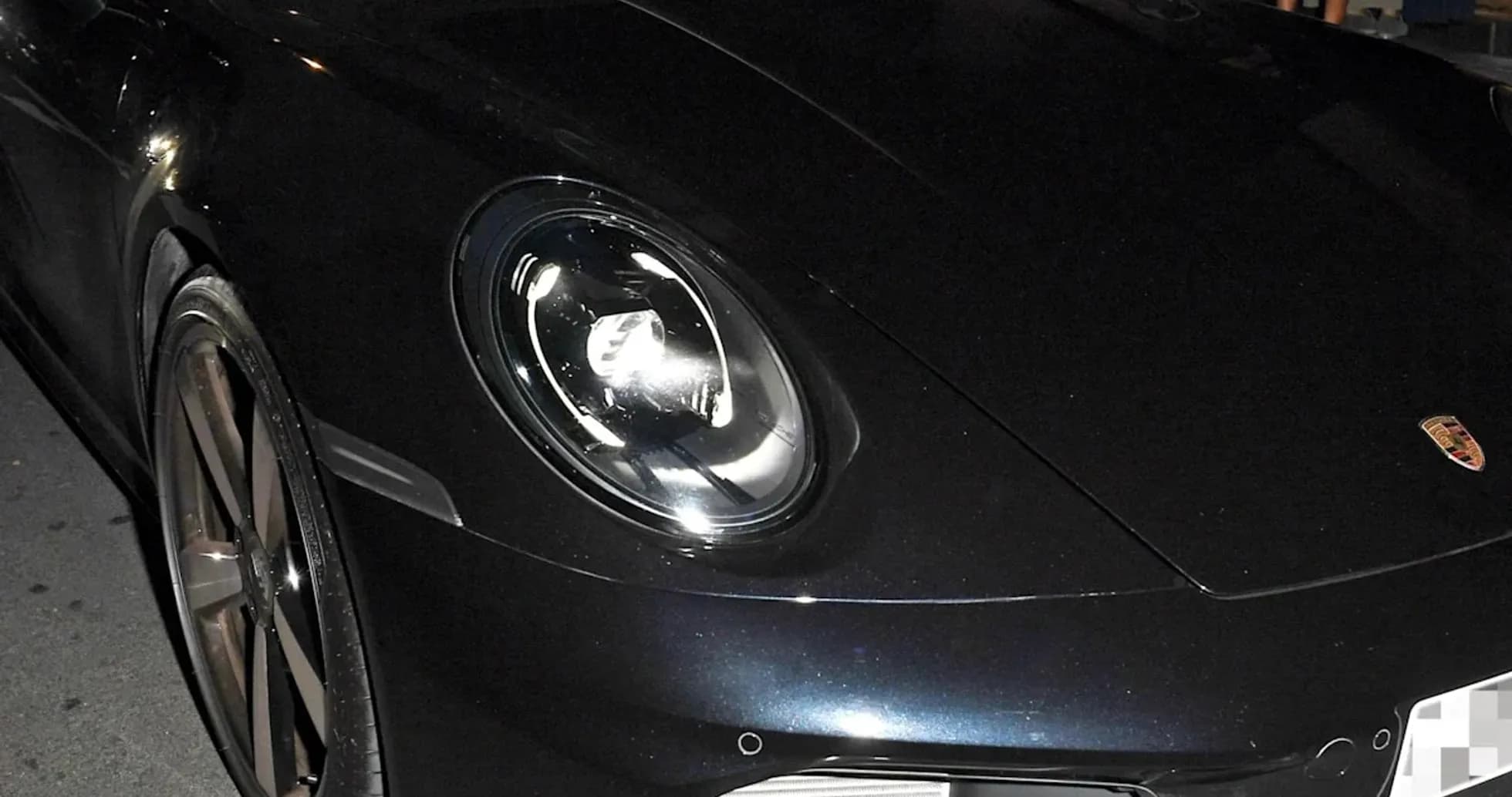 Two men inside a black Porsche car at night