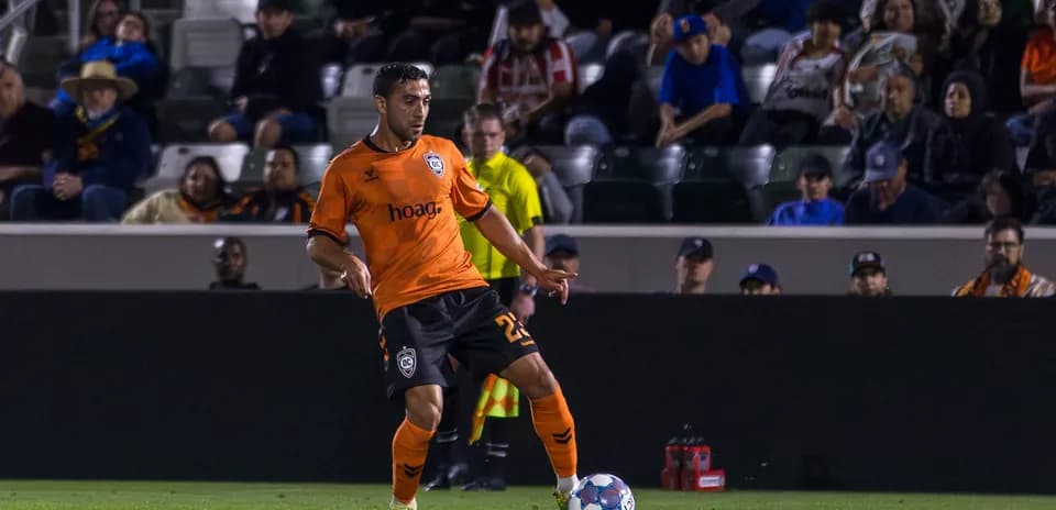 Player in orange kit preparing to kick ball
