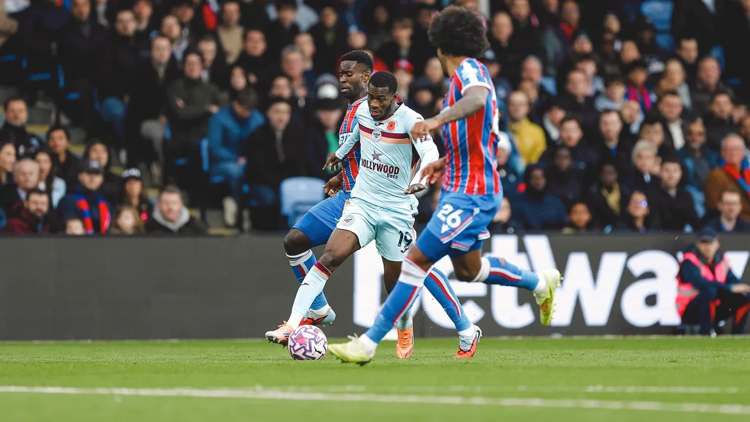 Brentford player challenged by Crystal Palace defenders