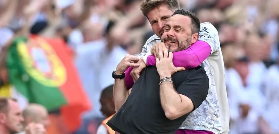 Two coaches celebrating in the stands after match