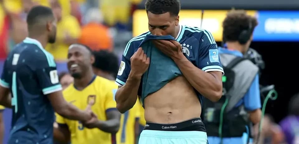 Player removing shirt after match with teammates nearby