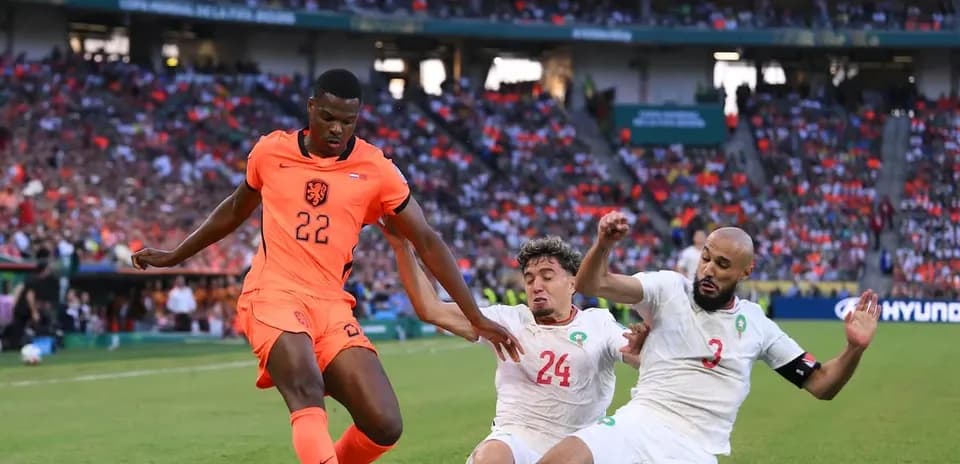 Player in orange jersey evading two defenders during match