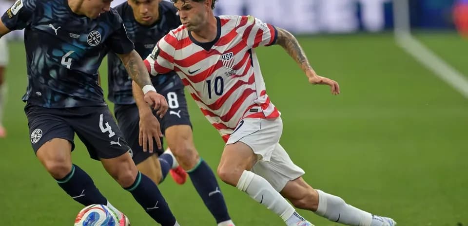 Christian Pulisic dribbling past defenders during match