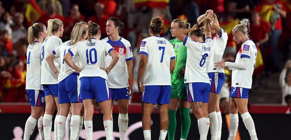 England women's team discussing strategy on the pitch