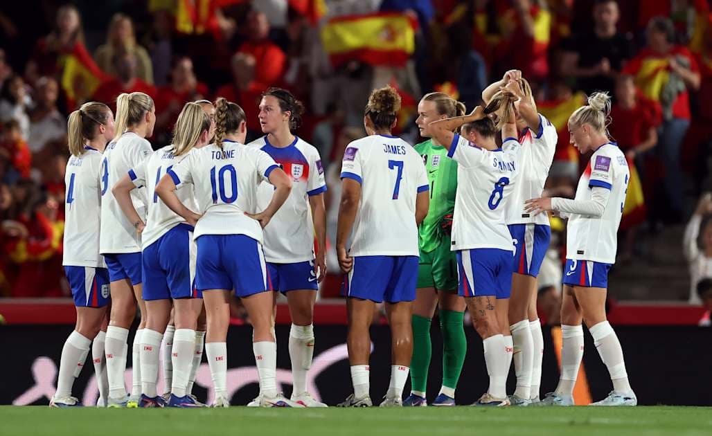 England women's team discussing strategy on the pitch