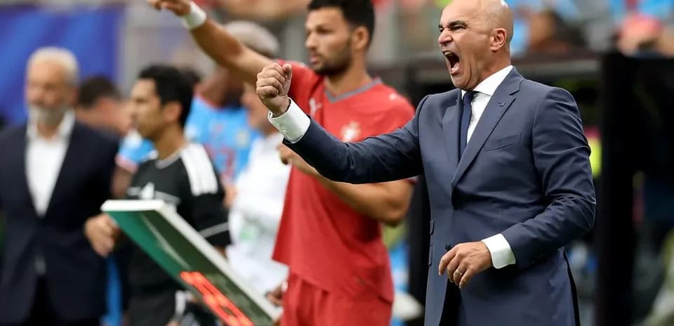 Coach celebrating a goal with players on bench
