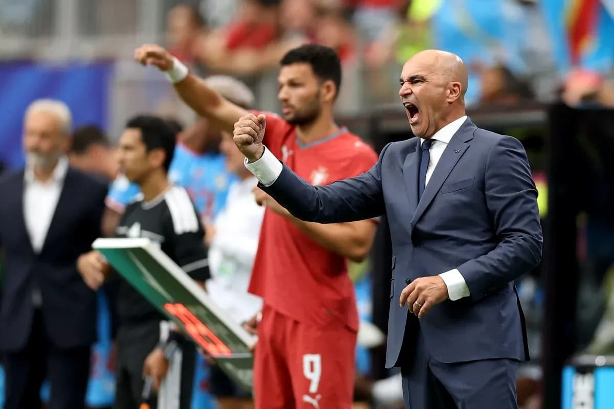 Coach celebrating a goal with players on bench