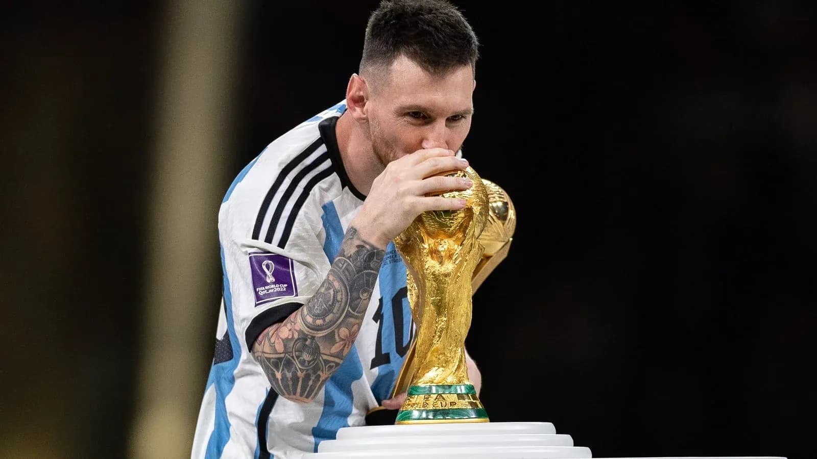 Player kissing FIFA World Cup trophy on stage