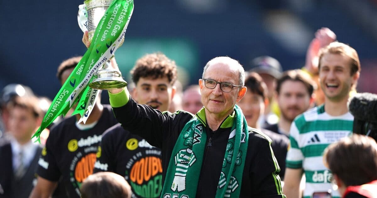 Manager holding trophy with celebrating players behind