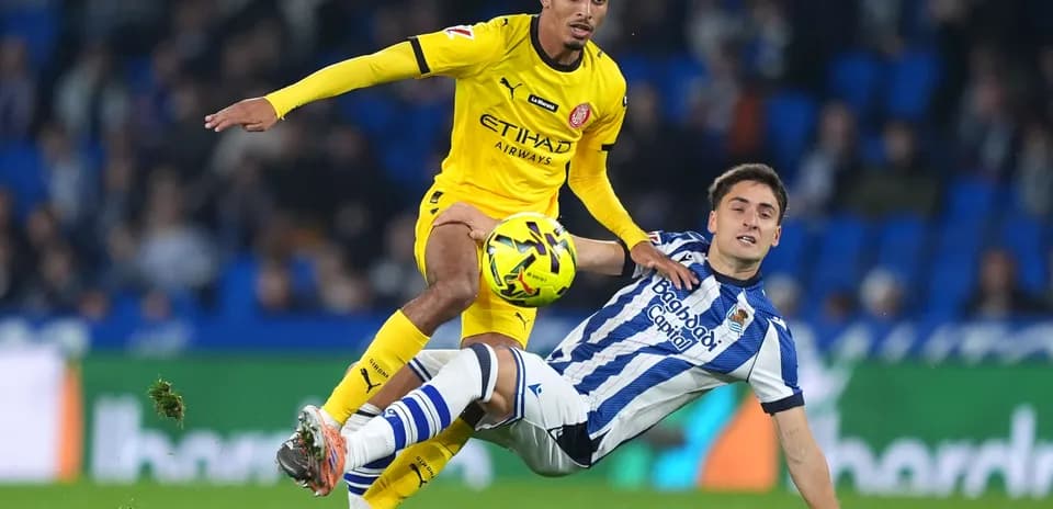 Girona player challenging Real Sociedad opponent