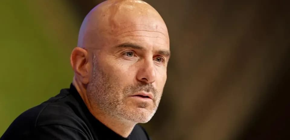 Manager speaking at press conference with serious expression