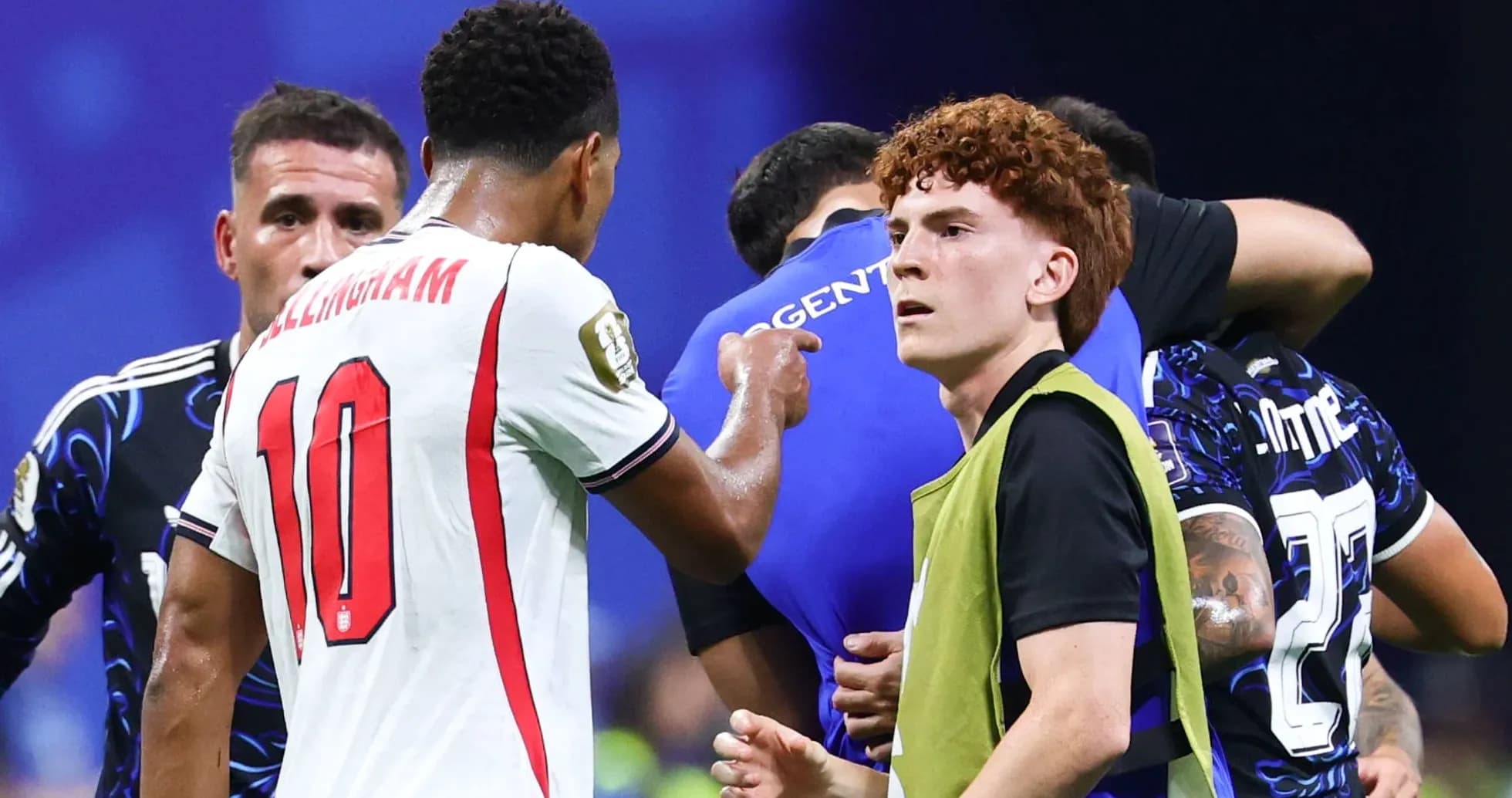 Players interacting during a match with substitutes nearby