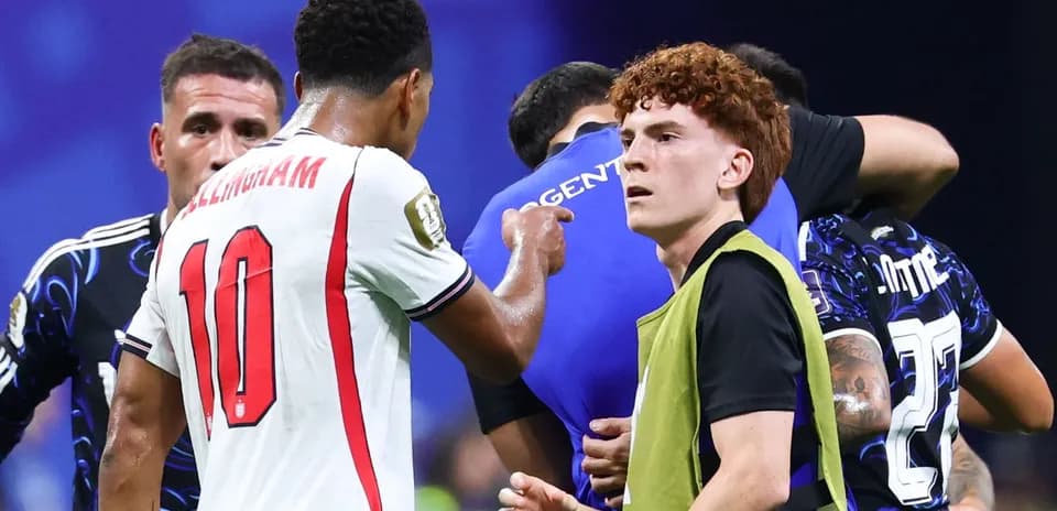 Players interacting during a match with substitutes nearby