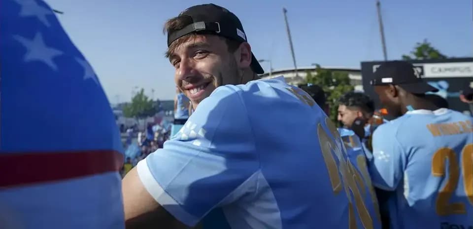 Player smiling in light blue jersey at celebration