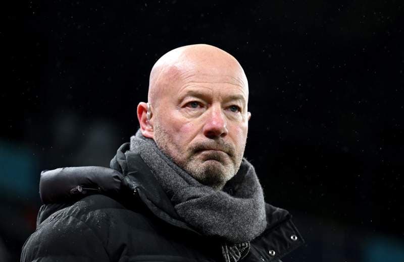 Man in coat and scarf observing a match