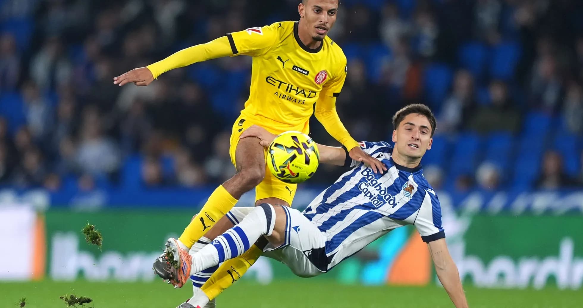 Player from Girona challenging Real Sociedad opponent
