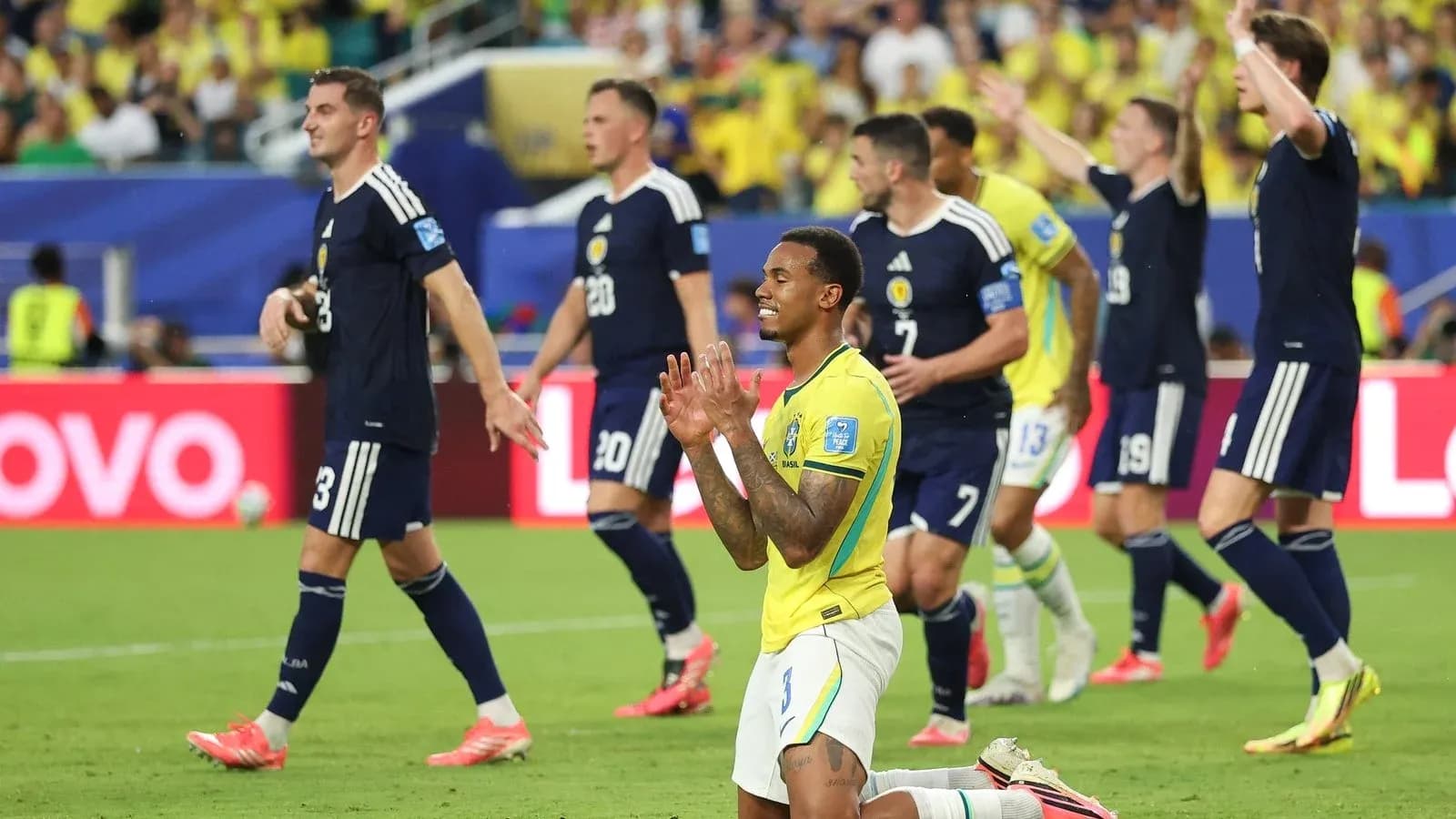 Brazilian player kneeling while Scottish players celebrate