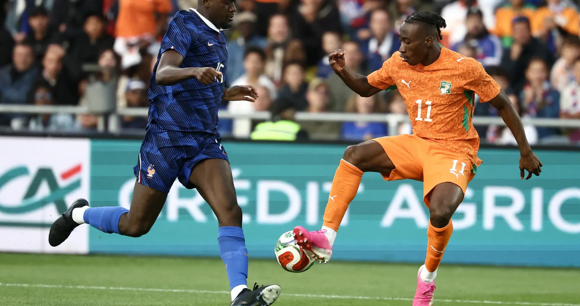 Player in orange dribbling past opponent in blue jersey
