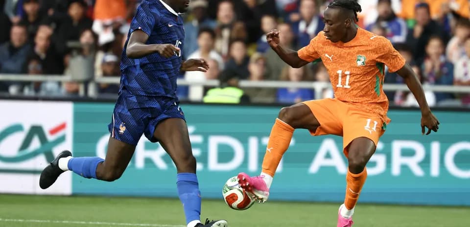 Player in orange dribbling past opponent in blue jersey