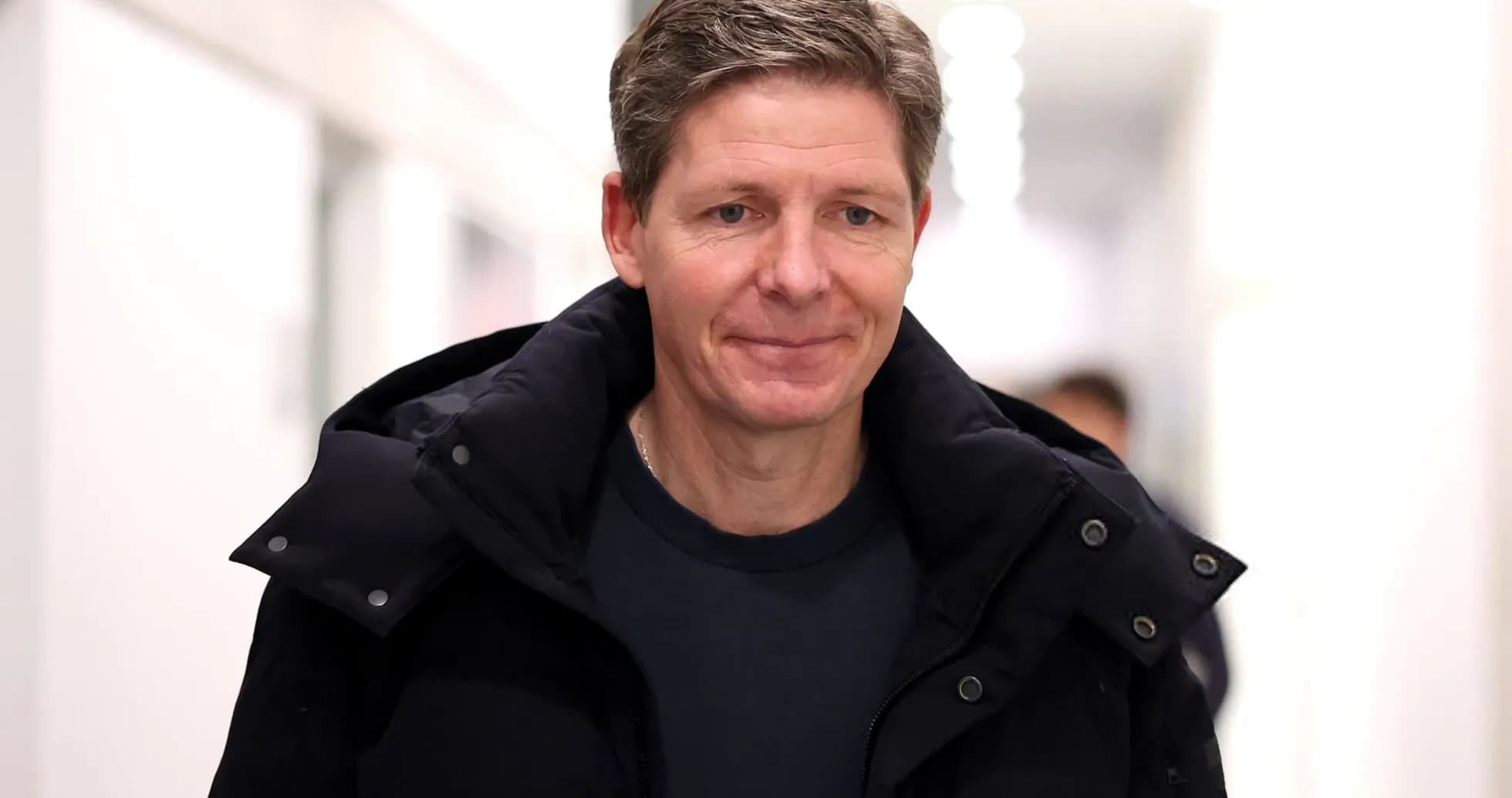 Person walking in a hallway wearing a black jacket