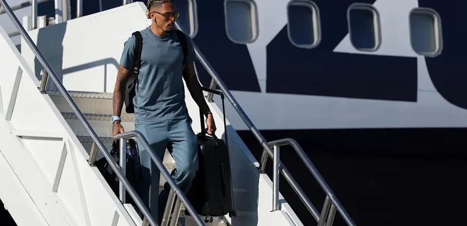 Player exiting airplane with luggage at airport