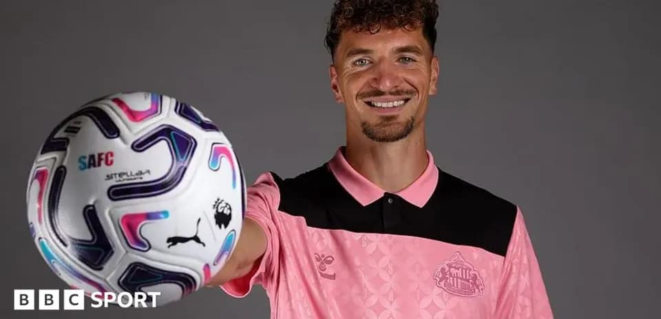 Player holding a football while smiling at camera