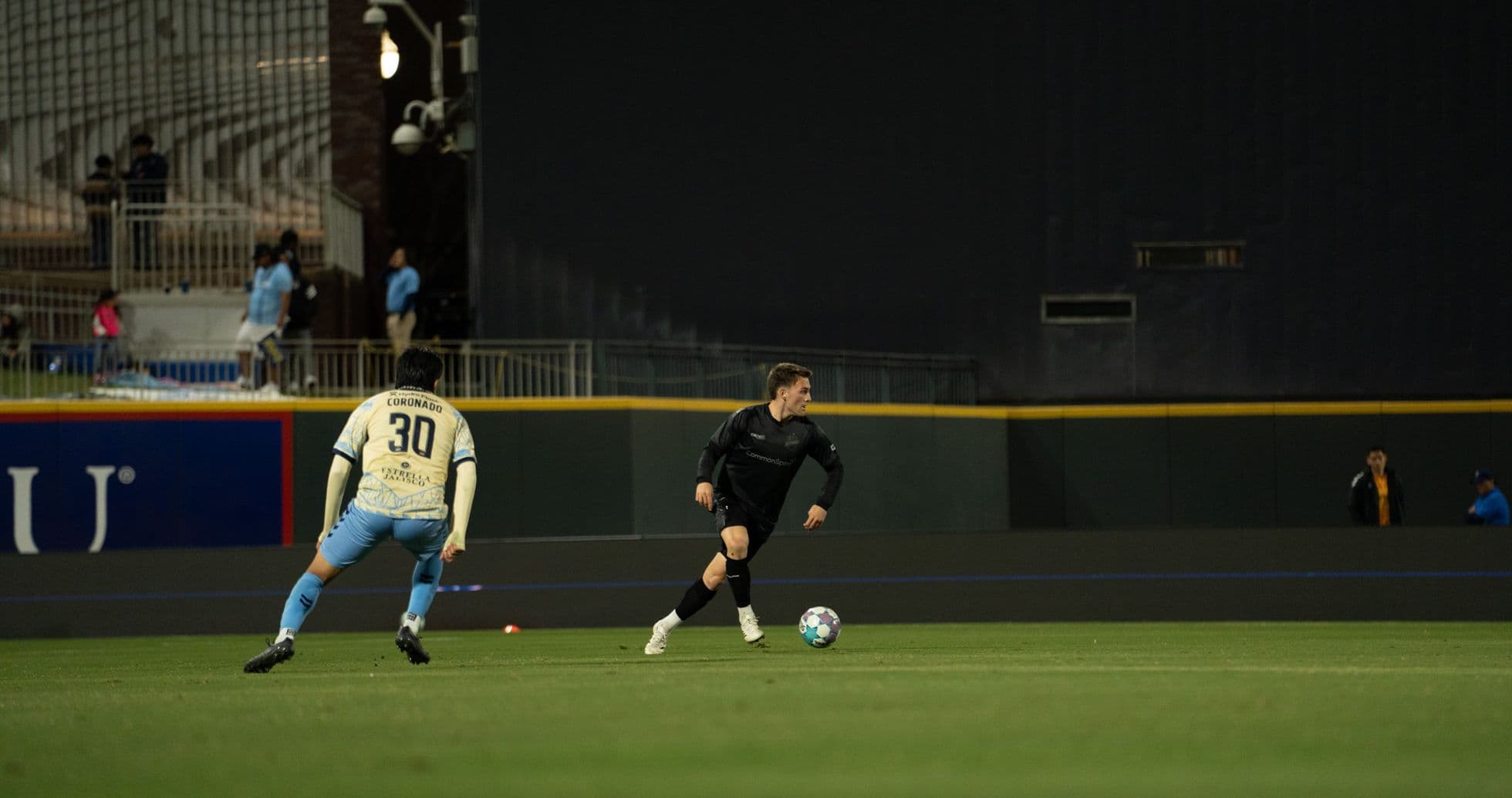 Player in black dribbling past defender in match