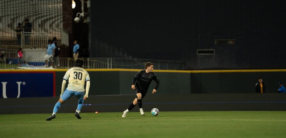 Player in black dribbling past defender in match