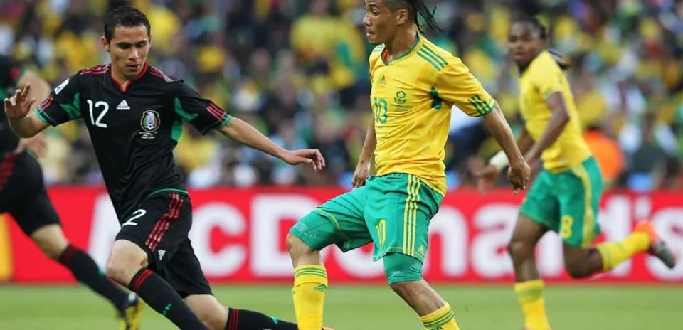 South African player dribbling past Mexican defender