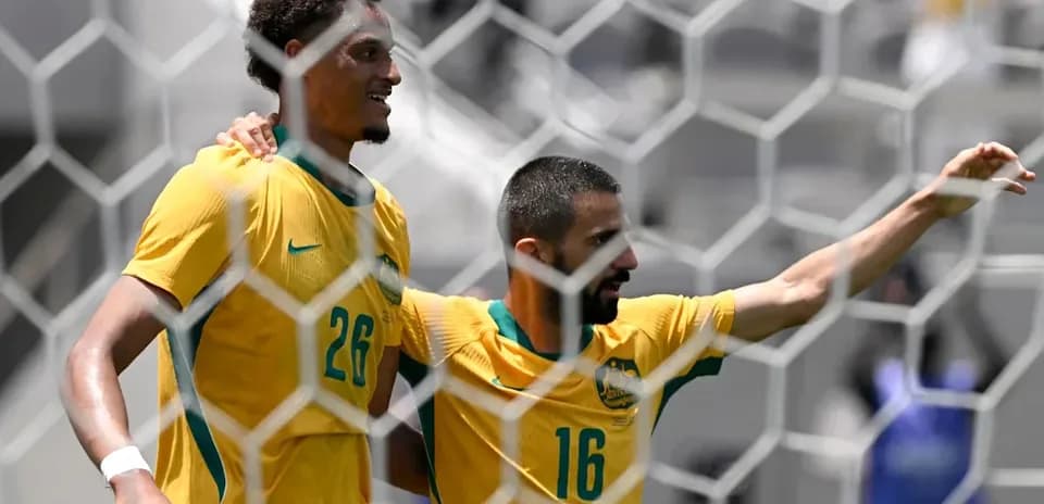 Two Australian players celebrating a goal on field